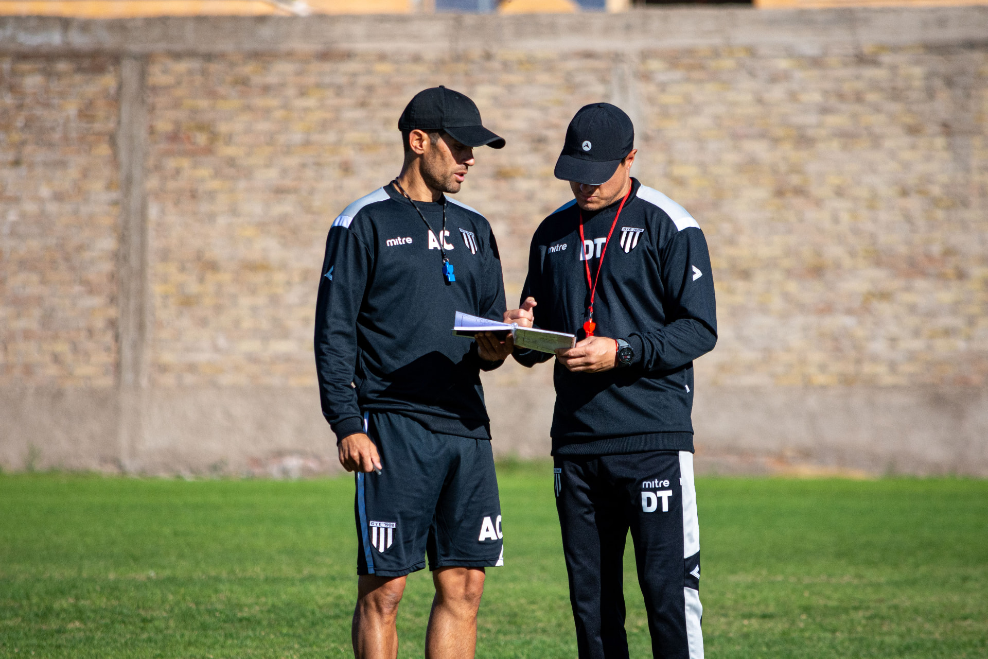 Two coaches reviewing notes on the pitch